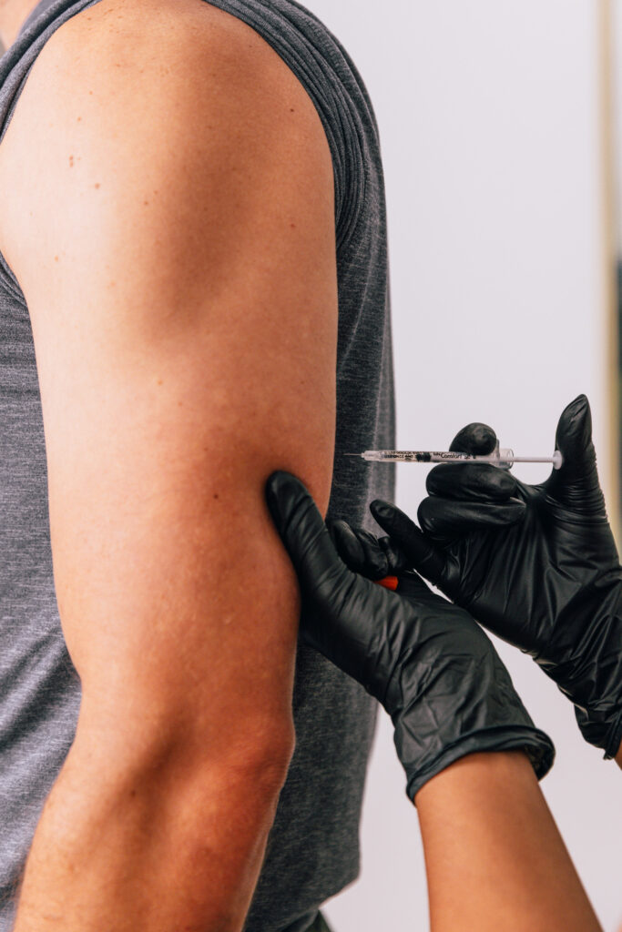 A provider at The Pip RX administers a patient's NAD+ injections in Lenexa. Wearing surgical gloves, the provider prepares to place the NAD+ injection in the patient's upper arm using an ultra-fine syringe.