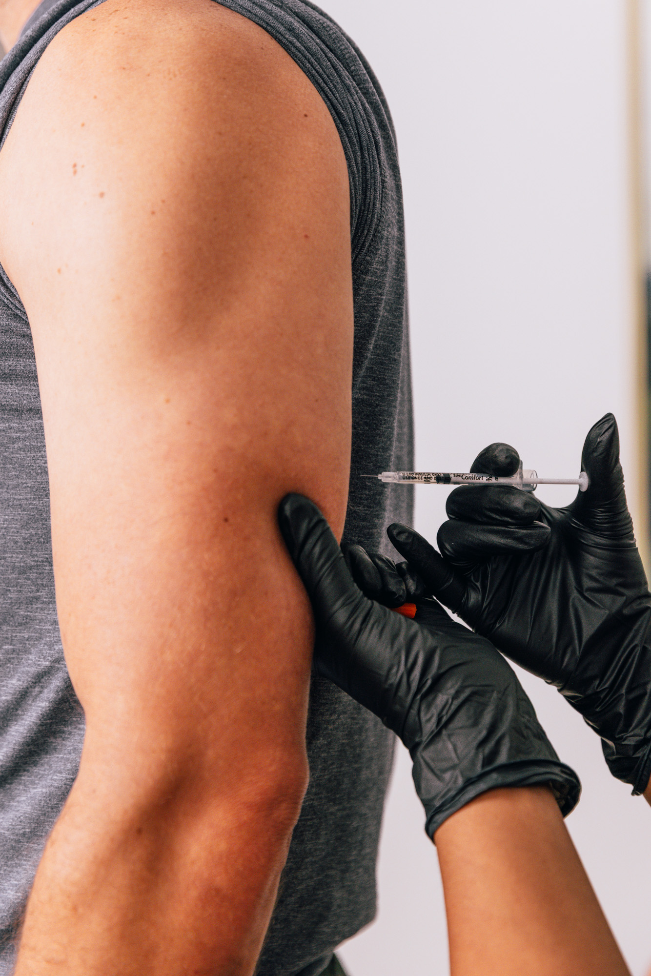 A provider at The Pip RX administers a patient's NAD+ injections, often used in a weight loss plan in Overland Park. Wearing surgical gloves, the provider prepares to place the NAD+ injection in the patient's upper arm using an ultra-fine syringe.